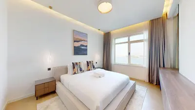 a white bedroom with a large bed and a window at Al Dabas - One Bed with Beach Access and Sea View in Dubai