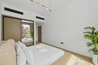 a white living room with a couch and a mirror at Golden Stays - Binghatti Crescent I Cozy 1BR Retreat I Pool & Gym I JVC Dubai in Dubai