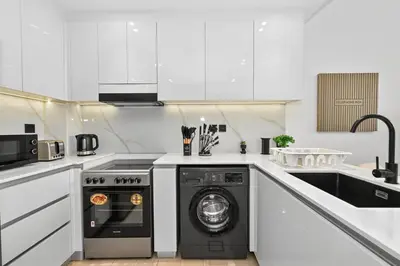 a white kitchen with a washing machine in it at Golden Stays - Binghatti Crescent I Cozy 1BR Retreat I Pool & Gym I JVC Dubai in Dubai
