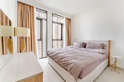 a white bedroom with a bed and large windows at Creek crescent high floor in Dubai