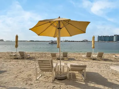 a yellow umbrella and chairs on a beach at Cozy Luxury One Bedroom Sea View on Private Beach and Infinity Pool in Dubai