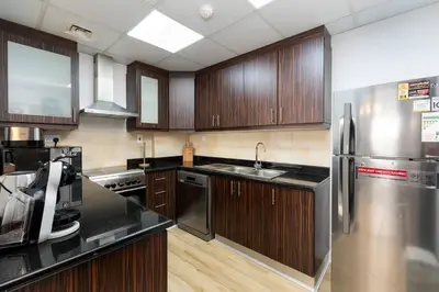 a kitchen with wooden cabinets and a stainless steel refrigerator at Jbr shams apartment in Dubai