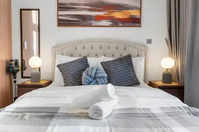 a bedroom with a white bed with two lamps at Studio in Azizi with Pool and Gym Access in Dubai