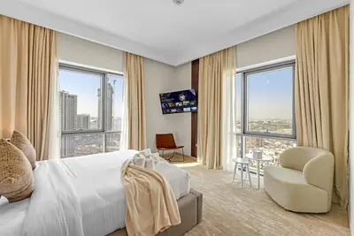 a hotel room with a bed and a chair and windows at Guest Favorite - Elegant & Stylish 2BR Stay at Vida Creek Harbour in Dubai