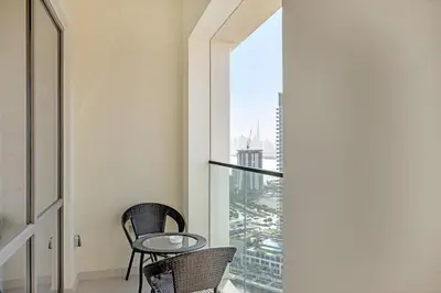 a balcony with two chairs and a glass table at Guest Favorite - Elegant & Stylish 2BR Stay at Vida Creek Harbour in Dubai