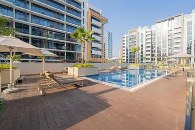 a pool with benches and umbrellas in a building at Chic Urban Studio in Dubai in Dubai