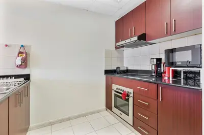 a kitchen with brown cabinets and a stove top oven at Chic 1BR with City Views Near Marina & Metro in Dubai