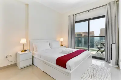 a white bedroom with a bed and a large window at Chic 1BR with City Views Near Marina & Metro in Dubai