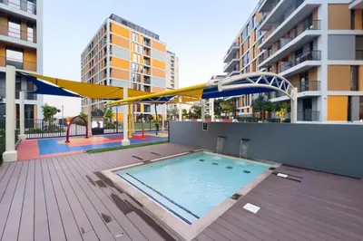 a swimming pool with an umbrella on a building at Amazing 2BR Peaceful Views in Midtown Near Sports City in Dubai