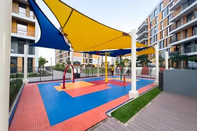 a playground with a large yellow and blue umbrella at Amazing 2BR Peaceful Views in Midtown Near Sports City in Dubai