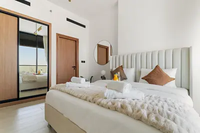 a bedroom with a large white bed with towels on it at VayK - Brand New and Bright 1BR in JVC in Dubai