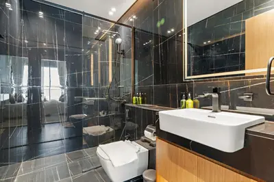 a black tiled bathroom with a sink and a toilet at VayK - Brand New and Bright 1BR in JVC in Dubai