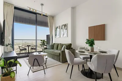 a living room with a couch and a table and chairs at VayK - Brand New and Bright 1BR in JVC in Dubai