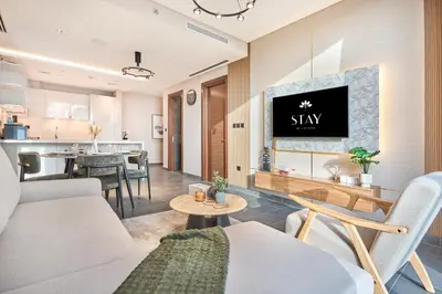 a living room with a couch and a tv on a wall at STAY BY LATINEM Luxury 2BR Holiday Home CC 1014 Near Burj Khalifa in Dubai