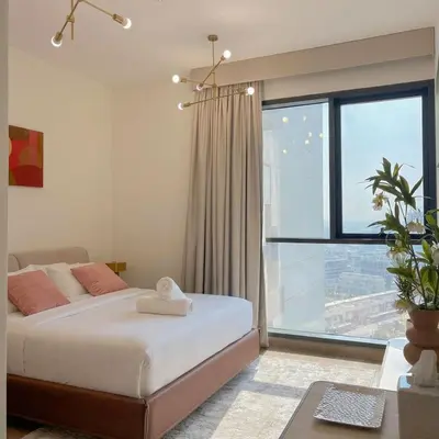 a bedroom with a bed and a large window at Gym Spa Padel & E-scooter Designer Brand New 2BR in Dubai