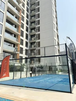 a tennis court in front of a tall building at Gym Spa Padel & E-scooter Designer Brand New 2BR in Dubai