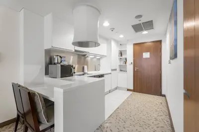 a white kitchen with a counter and a microwave at Abi Holiday Homes - Studio & 1BR Dubai Mall Fashion Avenue Residences in Dubai