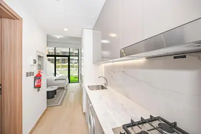 a white kitchen with a sink and a stove at Modern Studio, Swimming Pool, Balcony, and Close to Burj Khalifa in Dubai
