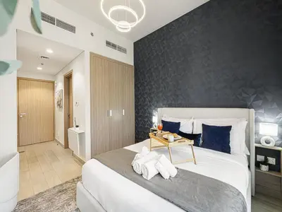a bedroom with a large bed with a black accent wall at Livin' Holidays - Studio - Azizi Near Downtown in Dubai