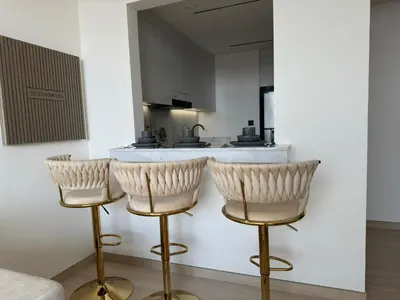 a kitchen with three bar stools in front of a counter at Stylish One Bedroom Apartment at Binghatti Crest, JVC Dubai By al sarya Holiday Homes in Dubai