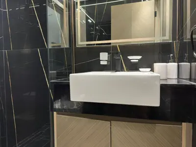 a bathroom with a white sink and black tiles at Stylish One Bedroom Apartment at Binghatti Crest, JVC Dubai By al sarya Holiday Homes in Dubai