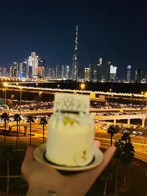 a person holding a wedding cake in front of a city at Elegant Apartment with Burj Khalifa View in Dubai