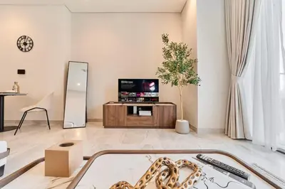 a living room with a tv and a table at FAM Living Dubai Escape Sleek Studio at Peninsula Five in Dubai