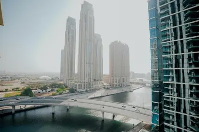a bridge over a river in a city with tall buildings at 2-Bed Apartment with Infinity Pool in Dubai