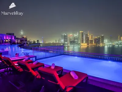 a swimming pool with red chairs and a city skyline at MarvelStay-Infinity Pool-Beachfront-The Palm in Dubai