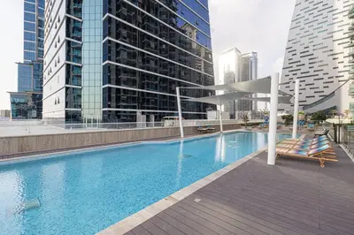 a swimming pool with two lounge chairs and buildings at Moon Stays - 5 PAX Missoni Flat - Canal View in Dubai