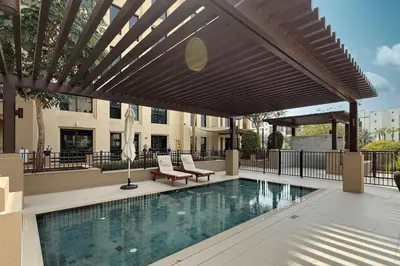 a swimming pool with a wooden pergola over it at StayMada - Lamtara Near Burj AlArab Beach Access in Dubai