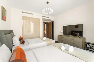 a bedroom with two beds and a television in it at Luxury 2BR in Sobha Hartland in Dubai