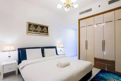 a white bedroom with a bed and a chandelier at Modern and Spacious 2BR in Glamz, Al Furjan in Dubai