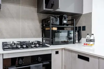 a kitchen with a stove and a microwave at TRPS - Alef Noon, JVC - Brand New - Luxury Furnished 1BR - Prime JVC Location in Dubai
