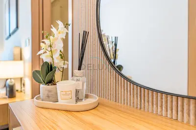 a vanity with a mirror and a bottle of soap and flowers at Luxury 1BR Stay, Connected to Dubai Mall and Burj Khalifa, Vida Dubai Mall Tower 2, Downtown Dubai by Deluxe Holiday Homes in Dubai