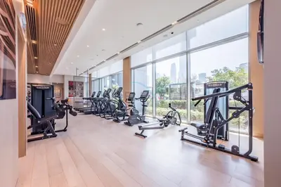 a gym with a row of treadmills and ellipticals at Luxury 1BR Stay, Connected to Dubai Mall and Burj Khalifa, Vida Dubai Mall Tower 2, Downtown Dubai by Deluxe Holiday Homes in Dubai