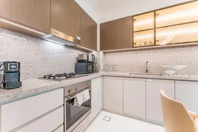 a kitchen with white cabinets and a stove top oven at Partial Sea Views with Private Beach Access, Near Dubai Marina and Palm Jumeirah, Grand Bleu Tower by Elie Saab, Tower 2, Emaar Beachfront by Deluxe Holiday Homes in Dubai