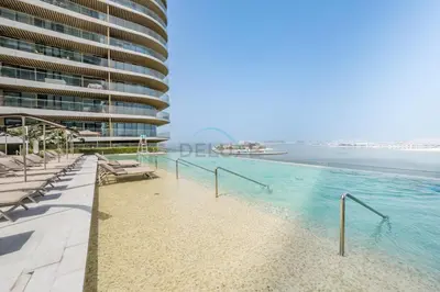 a swimming pool next to a tall building at Partial Sea Views with Private Beach Access, Near Dubai Marina and Palm Jumeirah, Grand Bleu Tower by Elie Saab, Tower 2, Emaar Beachfront by Deluxe Holiday Homes in Dubai