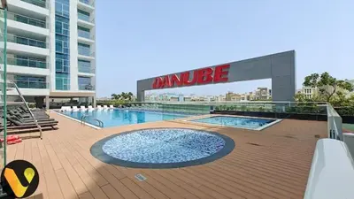 a large swimming pool in front of a large building at Vogue Al Furjan Pearlz by Danube near Ibn Battuta Mall, One Bedroom Apartment with Terrace and vibrant community view, Access to all Amenities, Walkable to Al Furjan Metro Station in Dubai
