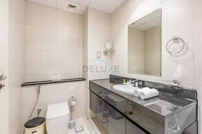 a bathroom with a sink and a toilet and a mirror at Studio Overlooking the Pool, Close to Parks, Grocery Stores, and Circle Mall, Damac Ghalia, JVC by Deluxe Holiday Homes in Dubai