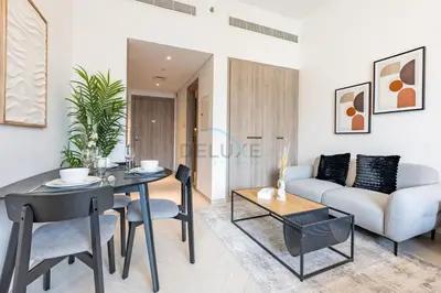 a living room with a table and a couch at Cozy Studio with Peaceful Community Views, Just Steps from Parks and Circle Mall, Oxford 212, JVC by Deluxe Holiday Homes in Dubai