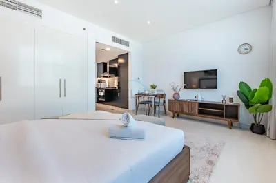 a bedroom with a large bed and a living room at Walking Distance to Bay Avenue Mall, 5 Minutes Drive to Downtown Dubai, Close to Metro Station, With Canal View, The Cosmopolitan, Business Bay by Deluxe Holiday Homes in Dubai