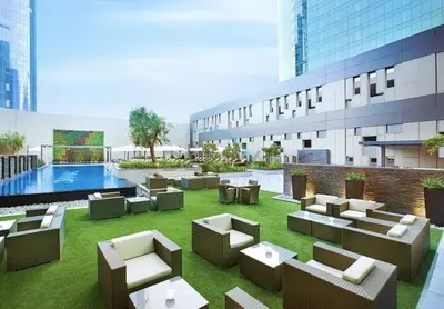a hotel patio with couches and a pool at Walking Distance to Bay Avenue Mall, 5 Minutes Drive to Downtown Dubai, Close to Metro Station, With Canal View, The Cosmopolitan, Business Bay by Deluxe Holiday Homes in Dubai