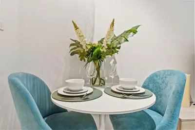 a white table with blue chairs and a vase with flowers at Seven Palm Studio Roof Top Pool Beach Gym for free in Dubai