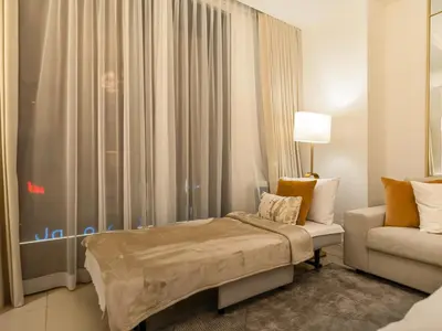 a bedroom with a bed and a couch and a window at Kensington Perfect 1BR Burj View and Dubai Mall Link in Dubai