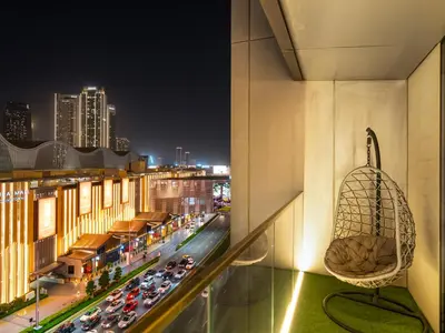 a chair on a balcony overlooking a city at night at Kensington Perfect 1BR Burj View and Dubai Mall Link in Dubai