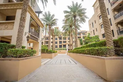 a walkway in a courtyard with palm trees and buildings at Bnbeyond Ultra-Luxe 2BR with Burj Khalifa Panorama in Dubai
