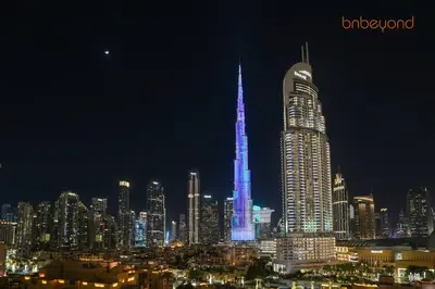 a city skyline with a tall skyscraper lit up at night at Burj Khalifa Light Show from your Bed in Dubai