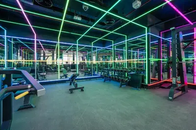 a gym with rows of machines and neon lights at Luxury Studio JVC Open View in Dubai