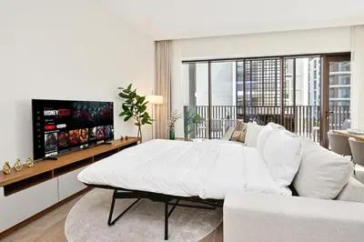 a white bedroom with a large bed and a tv at Modern 3BD with Maid's Room near Lagoon at Lotus 4 in Dubai